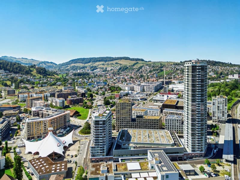 Aerial view of a modern urban area with high-rise buildings, green spaces, and a mix of residential and commercial structures.