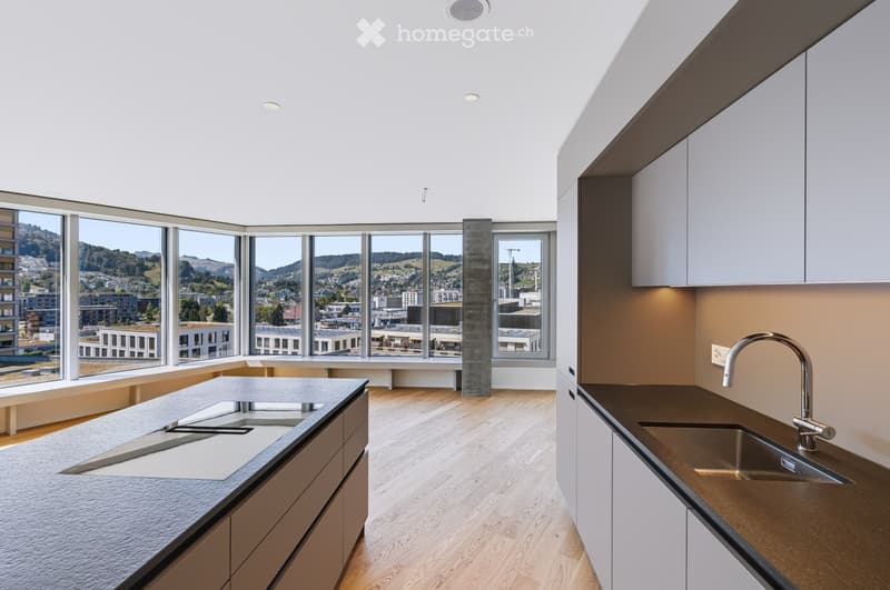 Modern kitchen with large windows offering a scenic view, featuring a central island with a sink, white cabinets, and a sleek faucet.