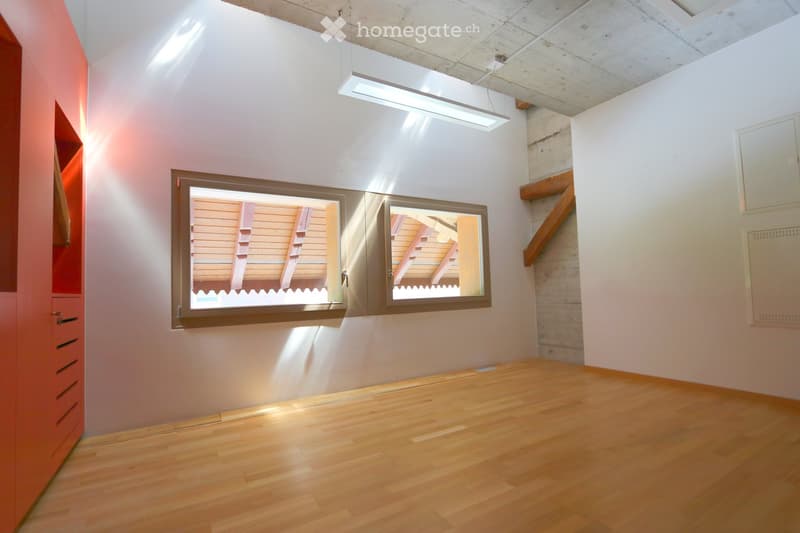 Empty room with wooden flooring, white walls, and a large window with shutters. A built-in wardrobe is visible on the left side.