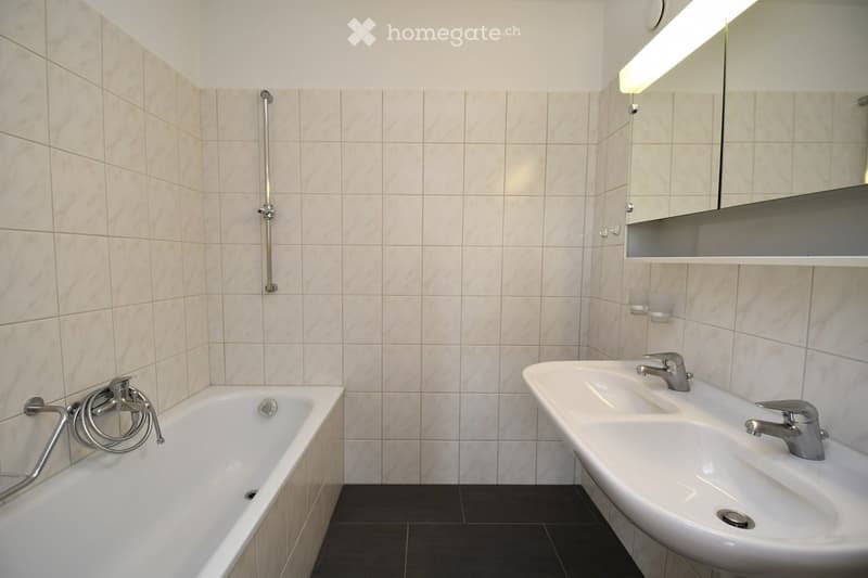 Bathroom with a bathtub, double sink, mirror, and modern fixtures.