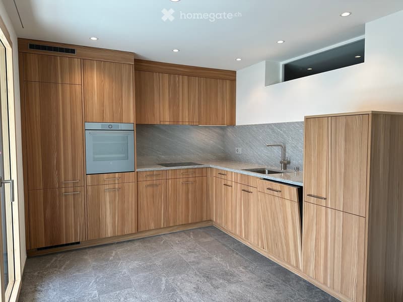 Modern kitchen with wooden cabinets, stainless steel oven, and granite countertop.