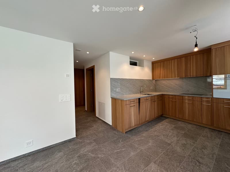 Modern kitchen with wooden cabinets, a sink, a faucet, and an oven. The space features tiled flooring and recessed lighting.