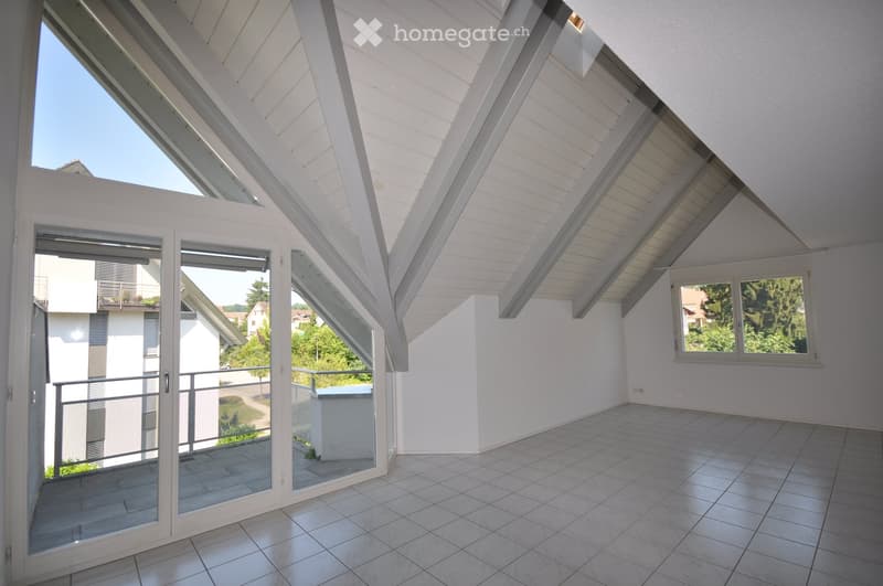 Bright, empty room with white walls, tiled floor, and large windows, including a sliding glass door leading to a balcony.