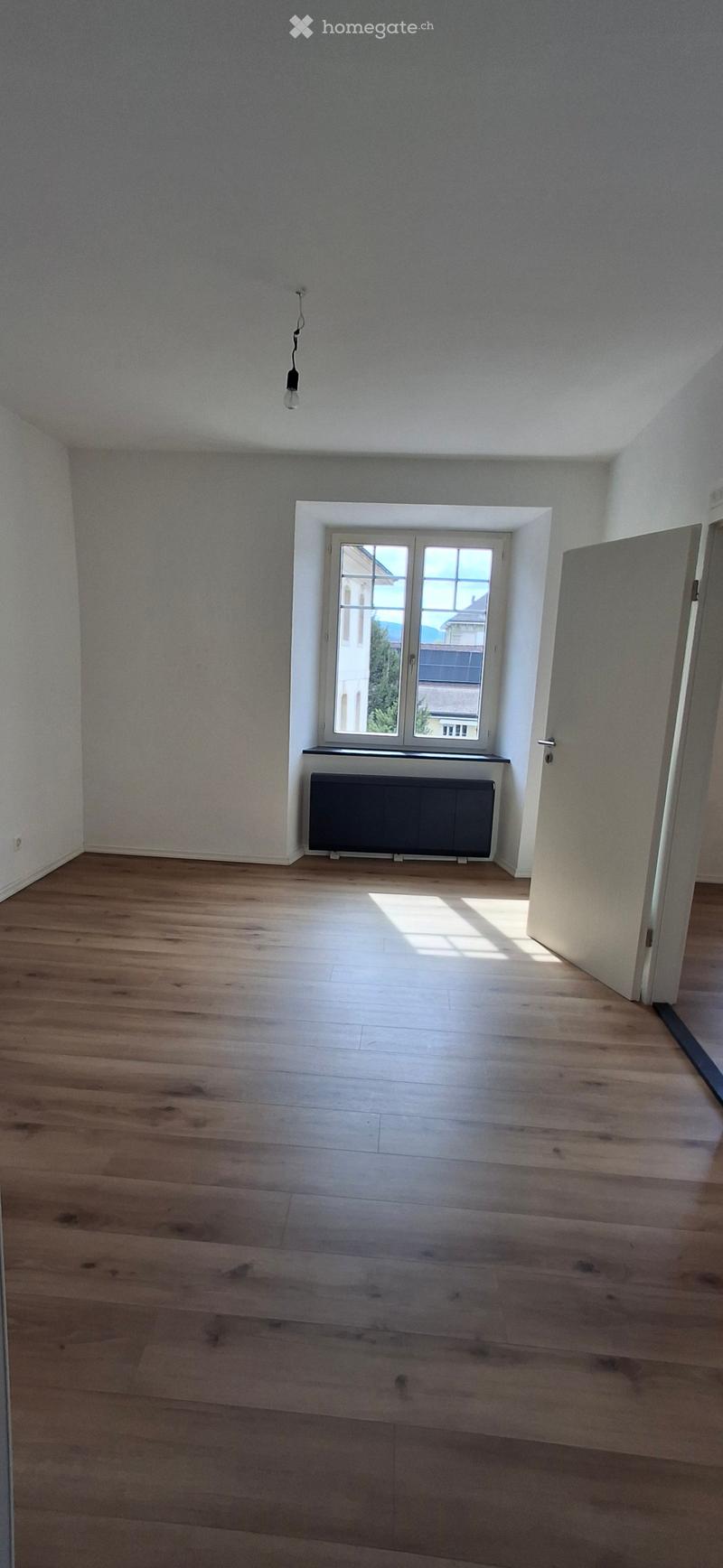 Empty room with light wooden flooring, white walls, and a window with a radiator below it. No furniture or equipment is present.