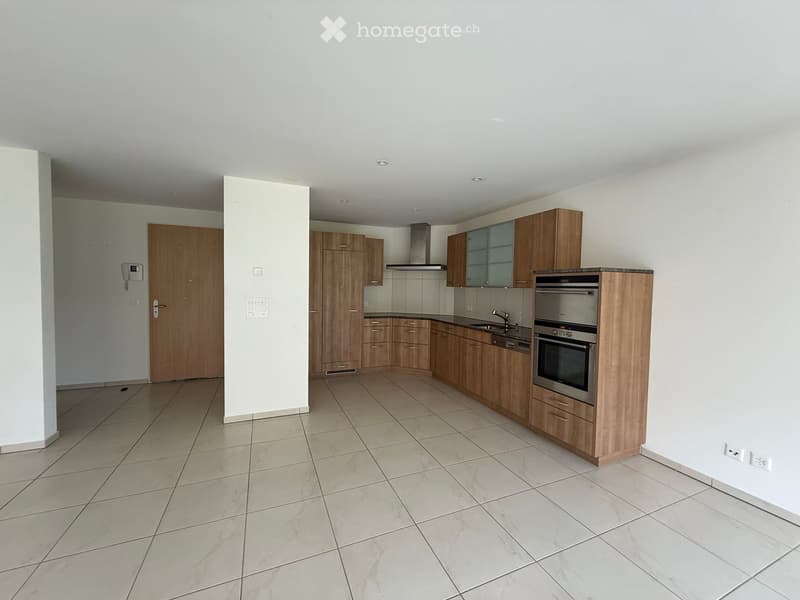 Modern kitchen with light wooden cabinets, stainless steel oven, sink, and faucet. The space features tiled flooring and white walls.