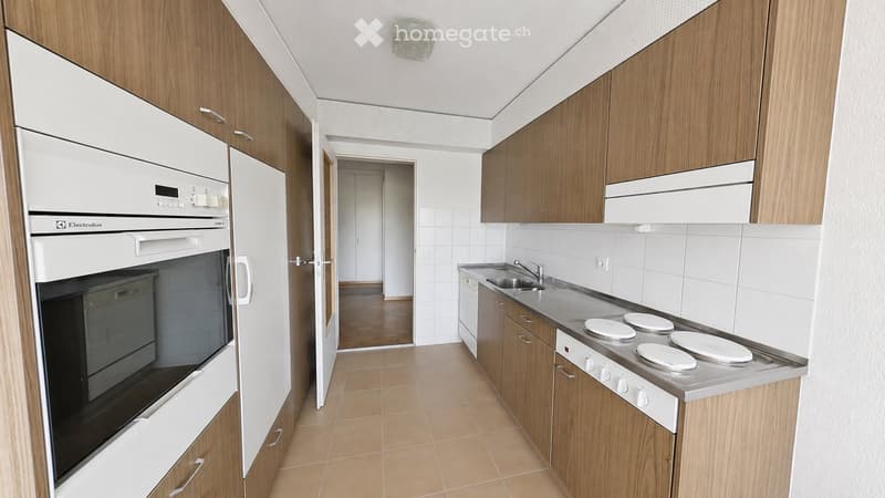 Modern kitchen with wooden cabinets, white appliances, a stainless steel sink, and a stove with four burners.