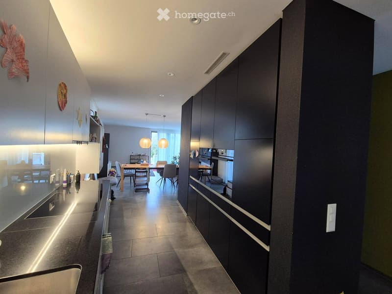 Modern kitchen with dark cabinets, a central island, and a dining area with a table and chairs.