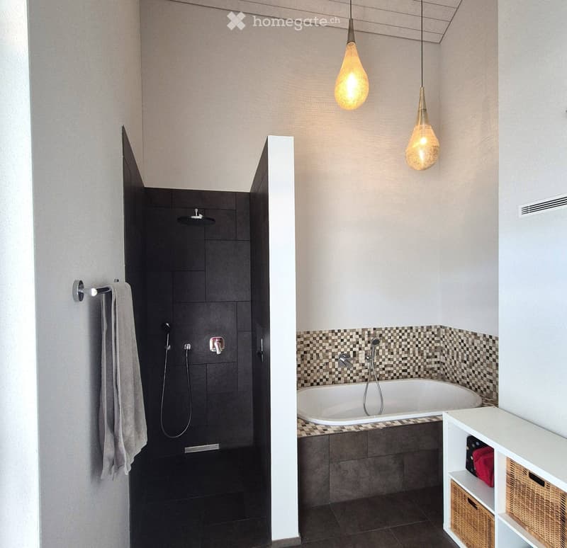 Modern bathroom with a bathtub, separate shower area, and a white storage unit with woven baskets. Features pendant lights and a checkered tile backsplash.
