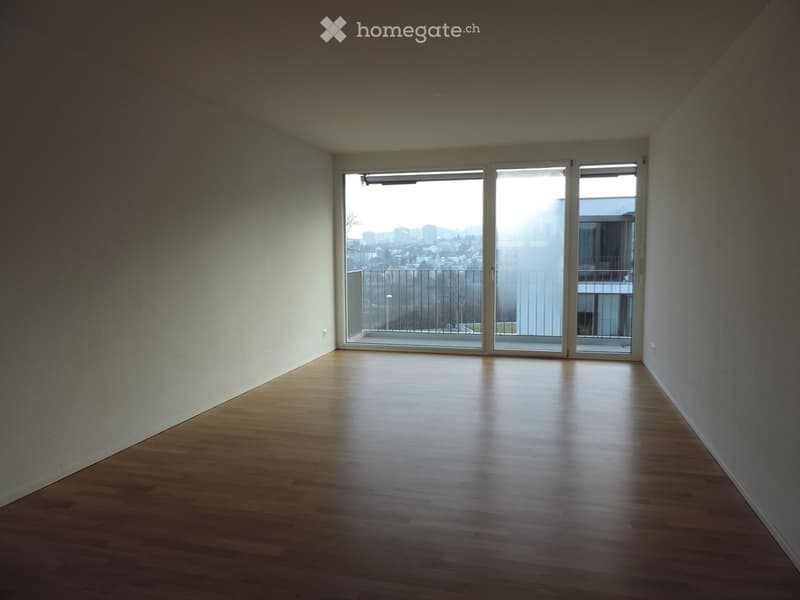 Empty room with wooden flooring and large sliding glass doors leading to a balcony with a city view.