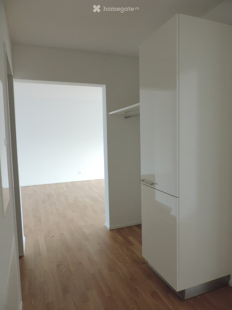 Empty room with wooden flooring, white walls, and a closet with shelves.