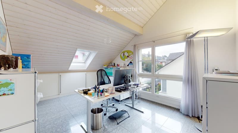 Bright, modern office space with wooden walls, large windows, and skylight. Features a desk with computer, chair, and various office supplies. Includes a cabinet, floor lamp, and decorative items like a map and statue.