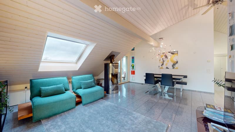 Modern living room with a skylight, fireplace, teal sofa, dining area, and chandelier.