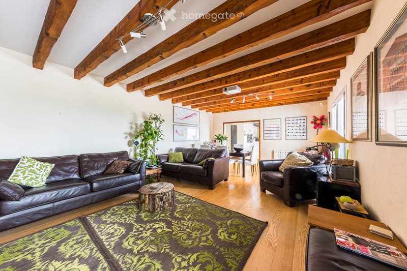 Living room with exposed wooden beams, leather sofas, coffee table, armchairs, side tables, and decorative plants.