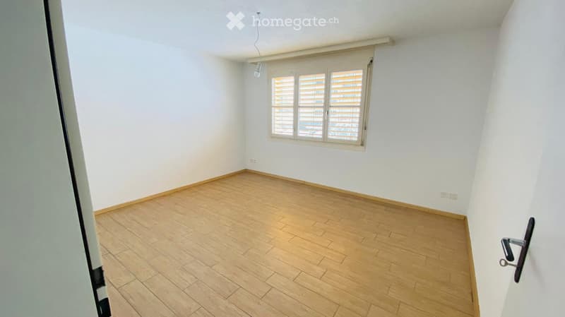 Empty room with light wooden flooring, white walls, and a window with blinds. No furniture or equipment present.