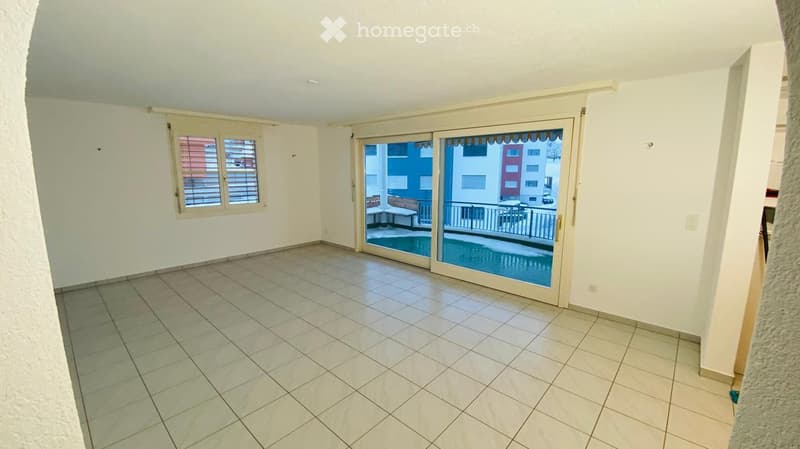 Empty room with tiled floor, white walls, large sliding glass doors leading to a balcony with a pool view.