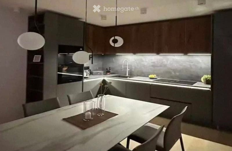 Modern kitchen with dark wooden cabinets, stainless steel appliances, a dining table with chairs, and a sleek faucet.