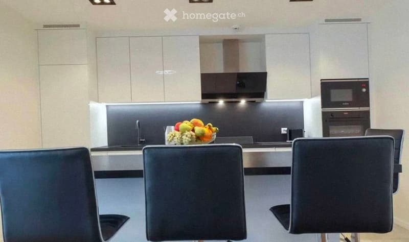 Modern kitchen with sleek cabinetry, stainless steel appliances, and a central island with seating.
