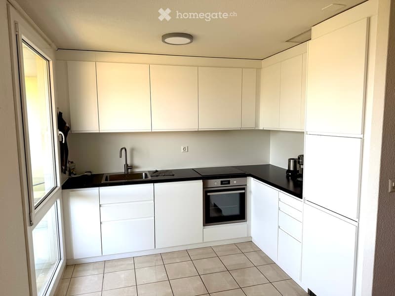 Modern kitchen with white cabinets, black countertops, stainless steel sink, and built-in oven.