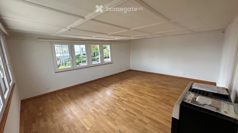 Empty room with wooden flooring, white walls, and large windows. No furniture or equipment present.