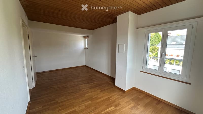 Empty room with wooden flooring, white walls, and large windows. No furniture or equipment present.
