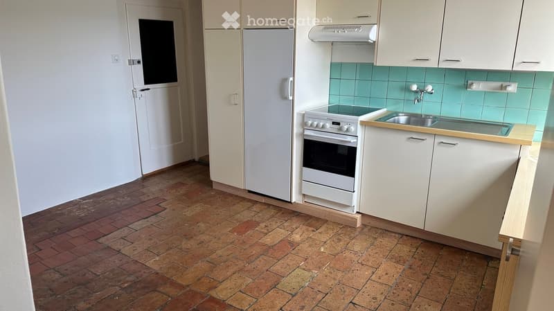 Modern kitchen with white cabinets, a refrigerator, an oven, and a sink, featuring a tiled backsplash and a brick floor.