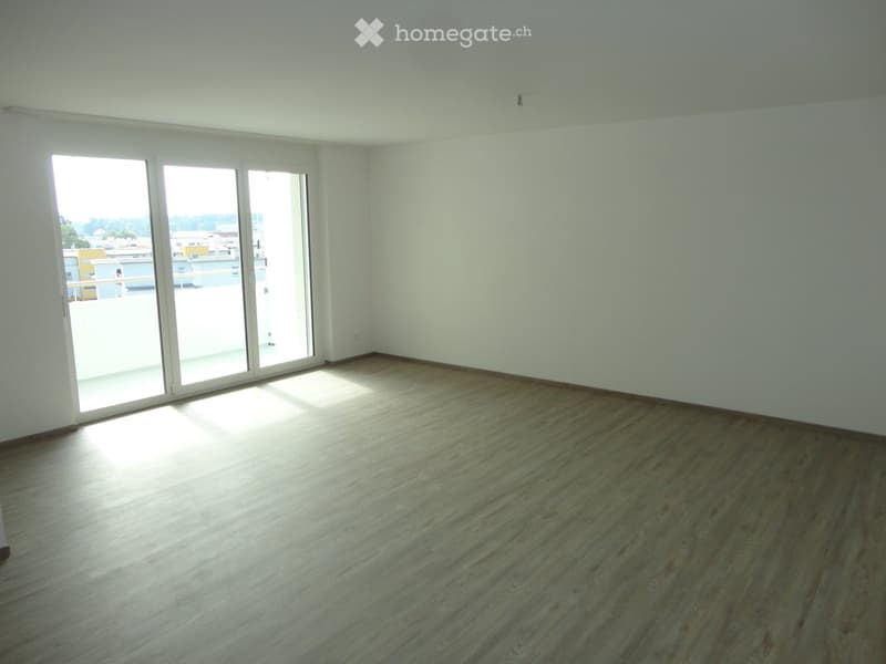 Empty room with wooden flooring and large sliding glass doors leading to a balcony.