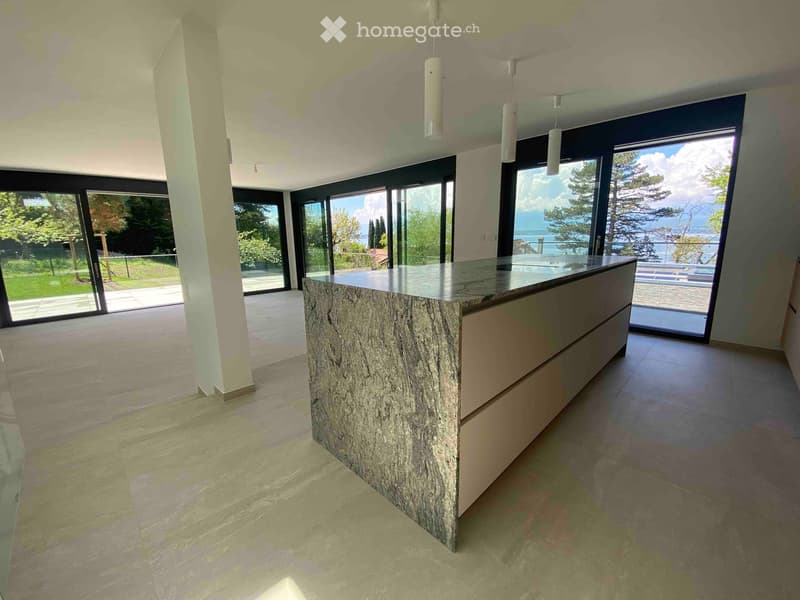 Modern kitchen with a central island, large windows offering a scenic view, and a minimalist design.