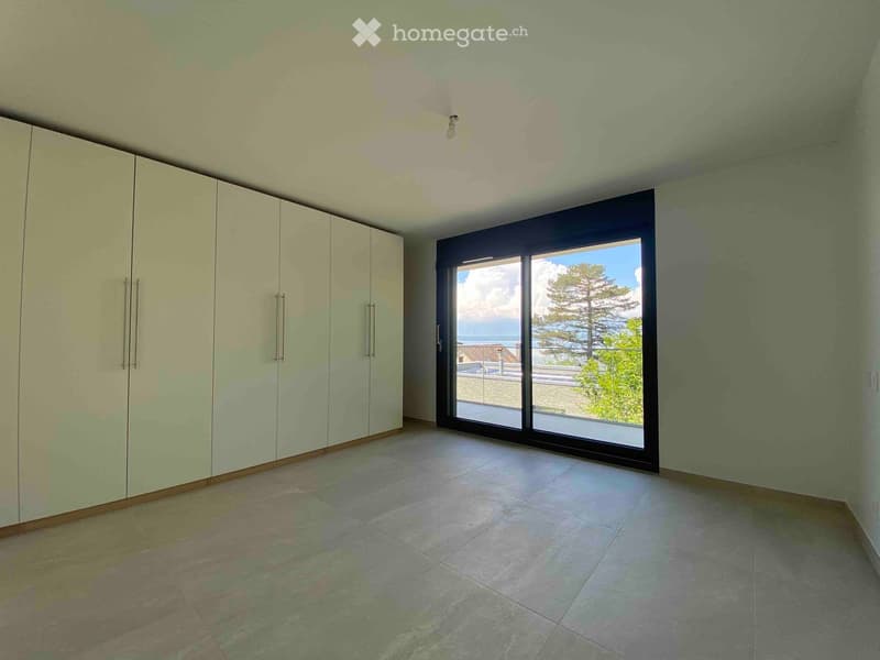 Empty room with large sliding glass doors offering a scenic ocean view, light green walls, and built-in wardrobes.