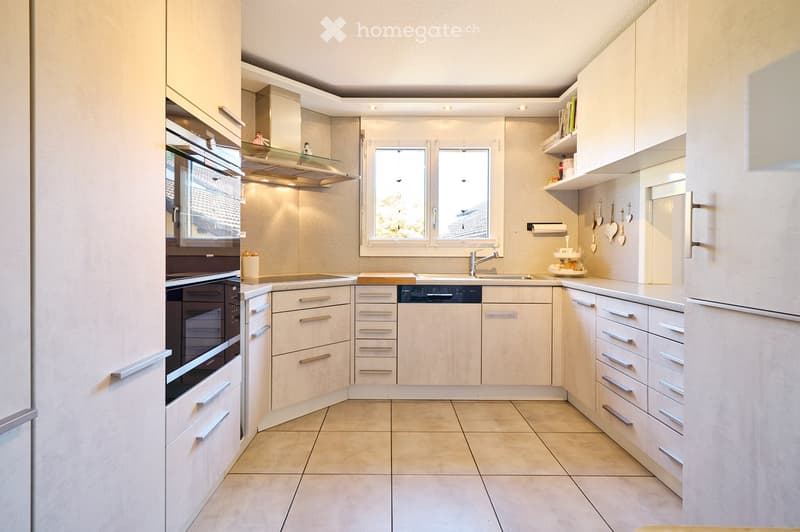 Modern kitchen with white cabinets, stainless steel appliances, and a tiled floor. Features include a refrigerator, oven, dishwasher, sink, and various kitchen utensils.