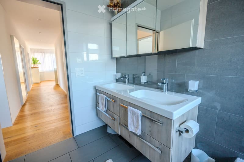double sink, under cabinet, mirrors, white tiles, wooden floor, towel holders