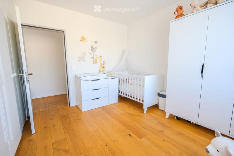 Wooden floor, white walls, crib with canopy, storage cabinet, wardrobe, trash bin, animal stickers on the wall
