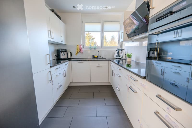 white cabinetry, tiled flooring, integrated appliances, large window