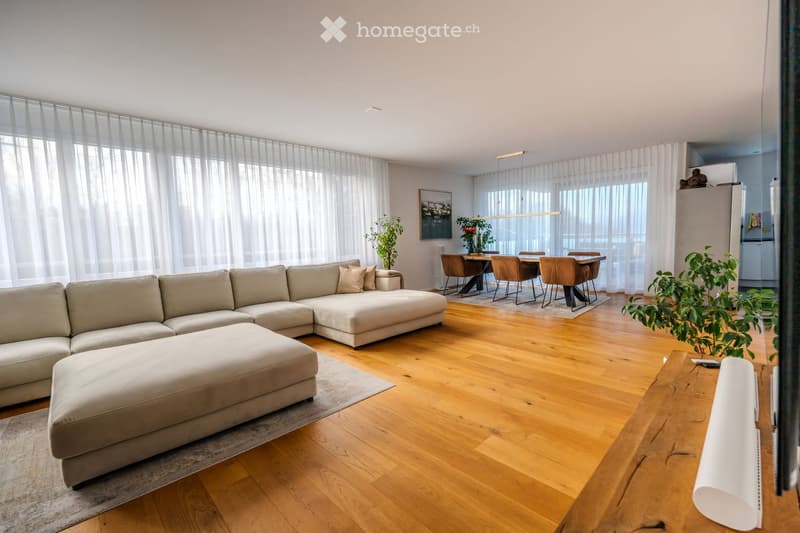 L-shaped beige sofa, footrest, wooden floors, white curtains, carpet, dining table with 6 chairs, dining rug, fridge, potted plants