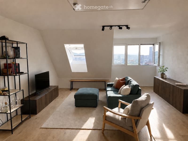 Modern living room with wooden flooring, large windows, and skylight. Features a green sofa, ottoman, armchair, TV, shelf, and small table.