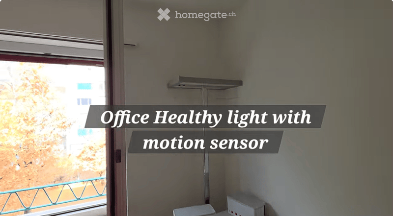 Empty room with a window and a motion sensor light fixture on the wall.