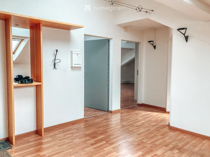 Empty hallway with wooden flooring, white walls, and a small built-in shelf with a mirror and a few items. There are two doors leading to other rooms.