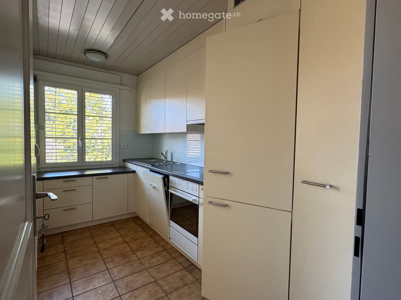 Modern kitchen with white cabinets, a sink, an oven, and tiled flooring.