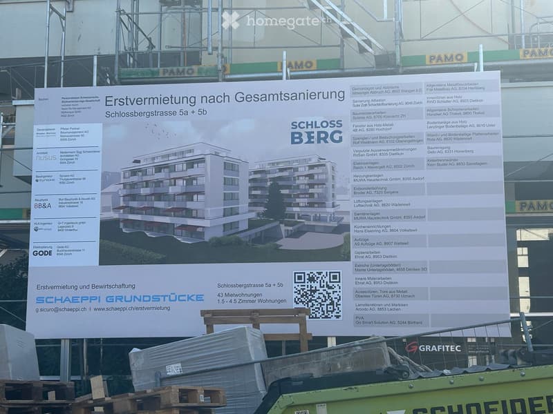 A large advertisement board displaying details about a property renovation and rental project, including a rendered image of the building and contact information.