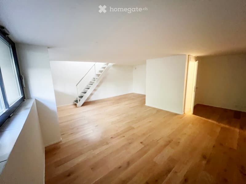 Empty room with wooden flooring, white walls, and a staircase leading upwards.