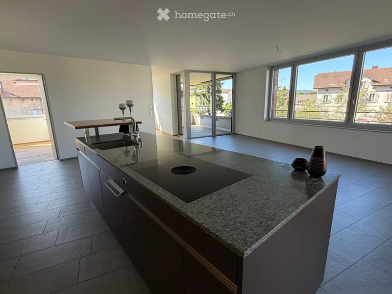 Modern kitchen with granite countertop, built-in sink, and cabinets. Features large windows and sliding glass doors leading to a balcony.