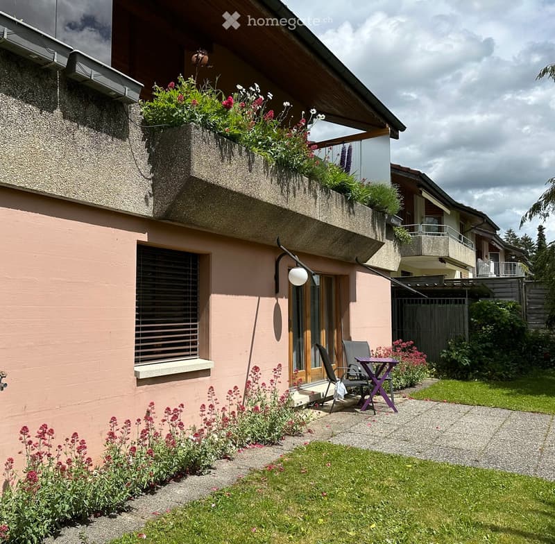 Garden area with a small patio, a table, two chairs, and various plants and flowers.