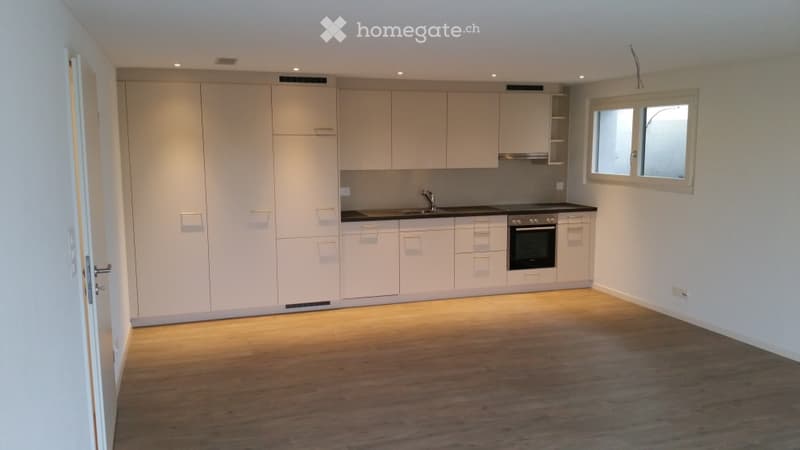 Modern kitchen with light-colored cabinets, a sink, a faucet, and an oven. The floor is wooden, and the space is well-lit with recessed lighting.