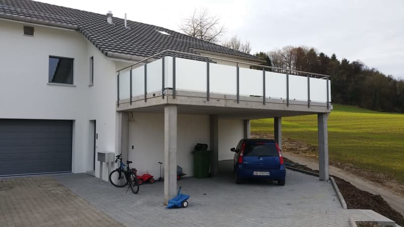 Two-story house with a garage, balcony, and a view of a green field.
