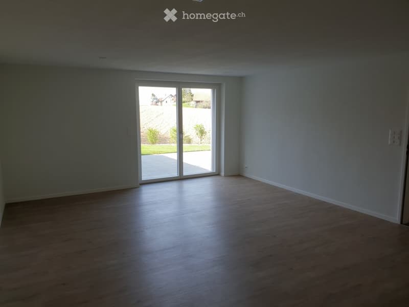 Empty room with wooden flooring and large sliding glass doors leading to an outdoor area.