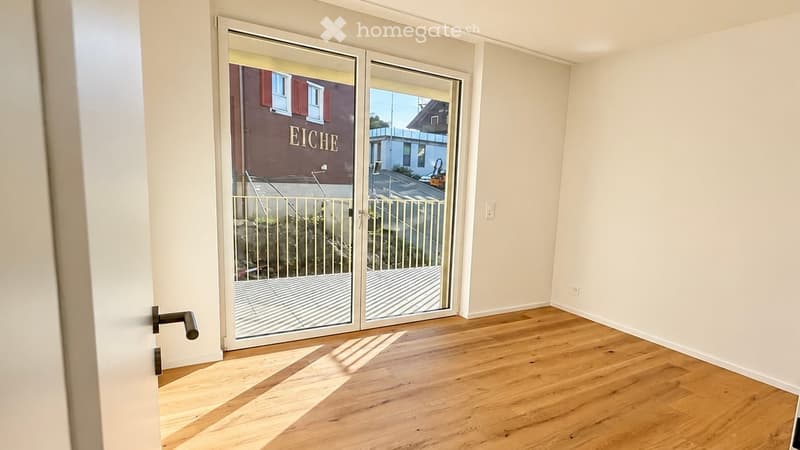 Empty room with wooden flooring and large sliding glass doors leading to a balcony area.
