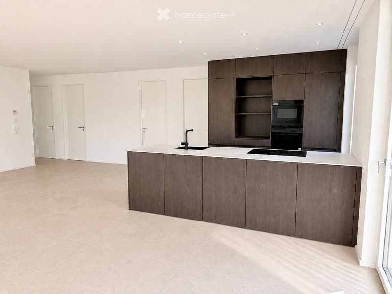 Modern kitchen with wooden cabinets, white countertops, and built-in appliances including a sink and oven.