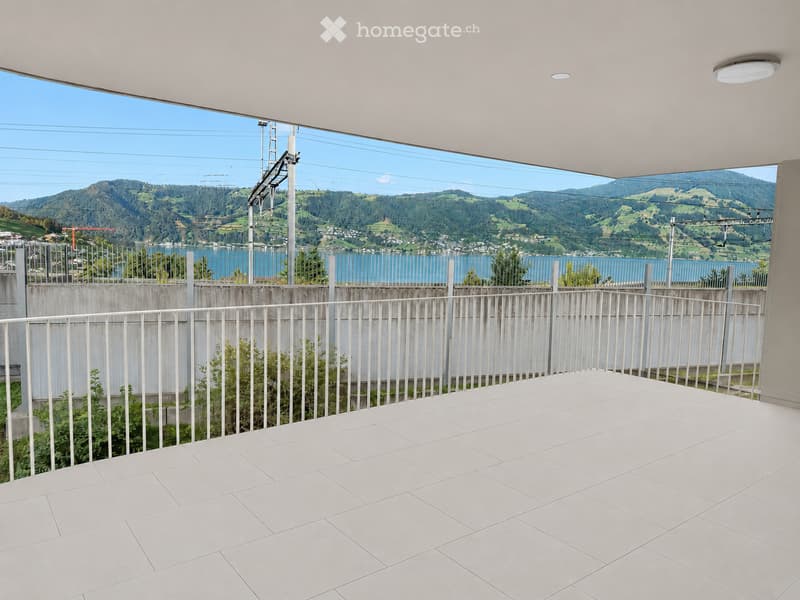 Balcony with white tiled floor, metal railing, and scenic mountain and lake view.