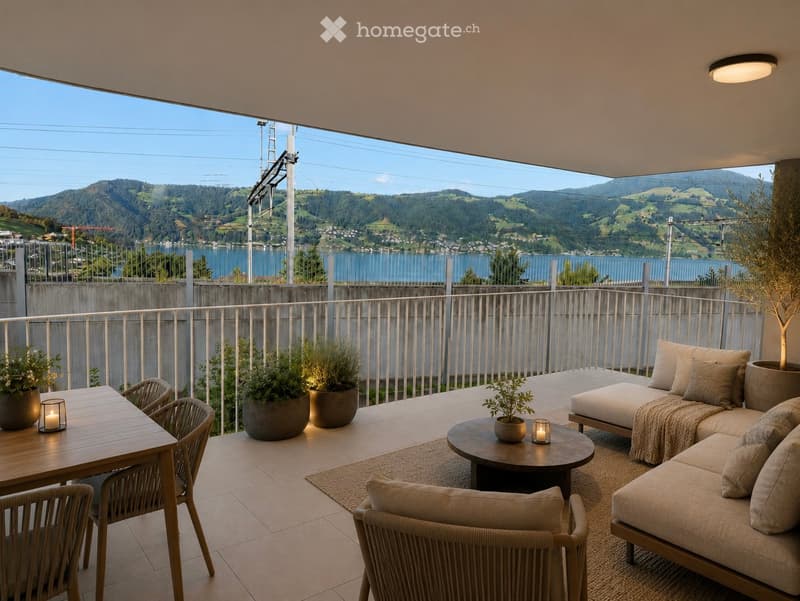 Balcony with a scenic mountain and lake view, furnished with a sofa, chairs, a table, and potted plants.