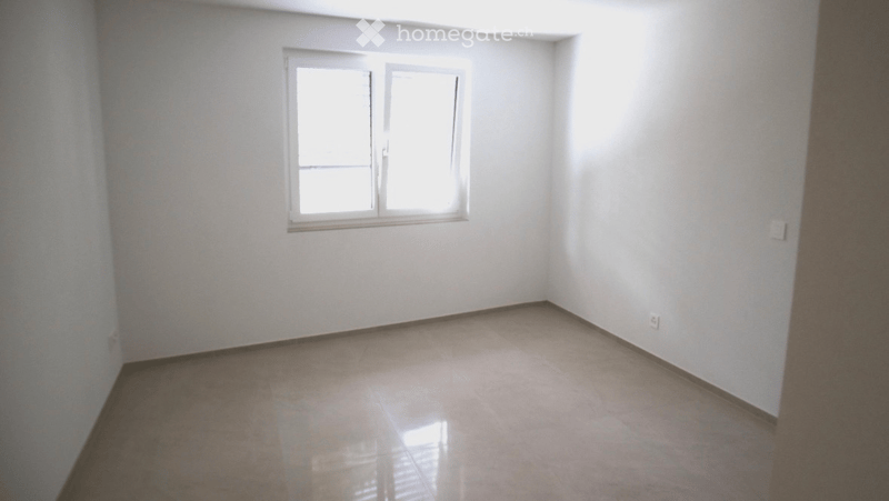 Empty room with white walls, tiled floor, and a single window with white frame.