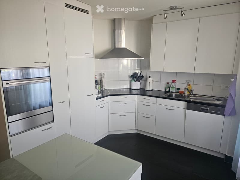 Modern kitchen with white cabinets, stainless steel appliances, black countertops, and a sleek design.